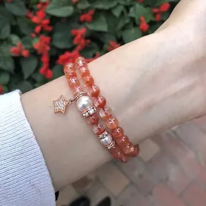 Detailansicht eines zweireihigen orangefarbenen Perlenarmbands mit Sternanhänger und Perlen