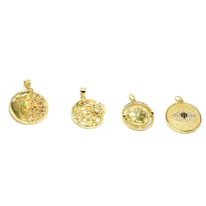 Group of four gold-colored jewelry charms with sun, moon, coin, and evil eye motifs.