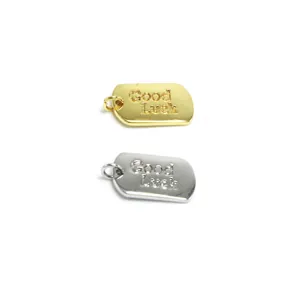 Detailansicht von rechteckigen Metallanhängern mit Good Luck Gravur in Gold und Silber