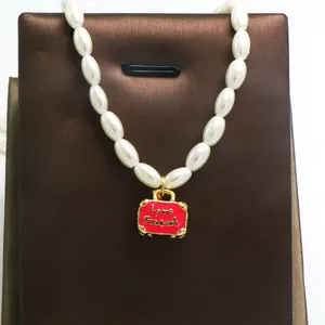 Detailed view of vintage faux pearl necklace with red enamel handbag pendant Love Travels