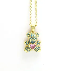 Close-up of golden teddy bear necklace with blue pavé zircons and a pink heart crystal