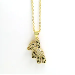 Detailed macro view of a gold-plated teddy bear pendant encrusted with clear and black zircons