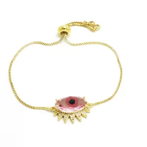 Detalle de pulsera ajustable de cadena dorada con dije de ojo turco de cristal rosa