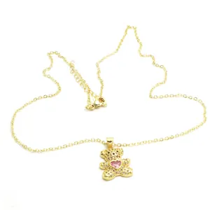 Close-up detail of a gold-plated teddy bear necklace featuring a pink heart cubic zirconia