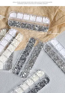 Dettaglio di contenitori a 12 griglie con perle e strass misti per la decorazione unghie.