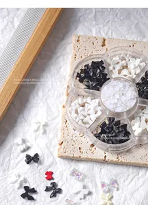 Gedetailleerde weergave van 7-vaks nail art kit met zwart-witte strikjes en parels