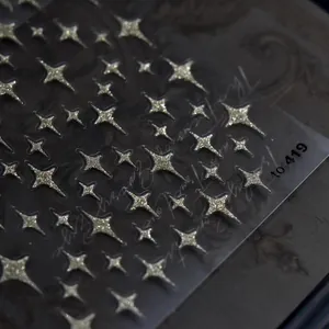 Macro detail of 3D gold glitter star nail stickers with embossed texture and shine.