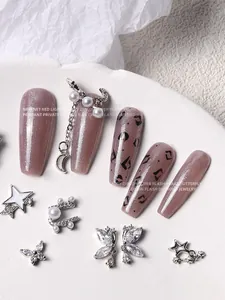 Close-up of luxury silver zircon nail art charms with butterflies, stars, and pearl chains.
