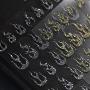 Macro view of metallic glitter flame nail art stickers in sparkly gold and silver