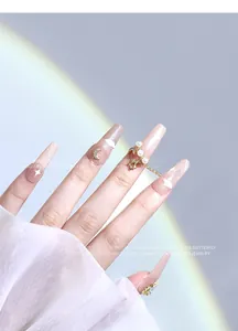 Détail de faux ongles élégants avec étoile en zircon, lune et bijoux en chaîne de perles
