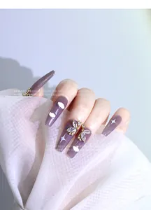 Détail macro de charms d'ongles papillon en zircon de luxe sur ongles violets