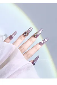 Gros plan de bijoux d'ongles papillon en zircon sur des ongles violets œil-de-chat.