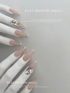 Funkelnde flache Nagel-Anhänger und Strasssteine auf langer Nude-Maniküre mit Glitzerspitzen