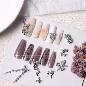 Luxury zircon butterfly and pearl nail art charms with silver chains on display.