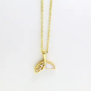 Close-up detail of a gold fish tail pendant necklace with rhinestones and white shell