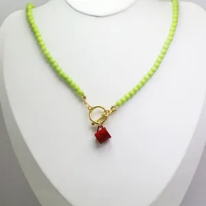 Close-up of lime green beaded necklace with red coffee cup charm