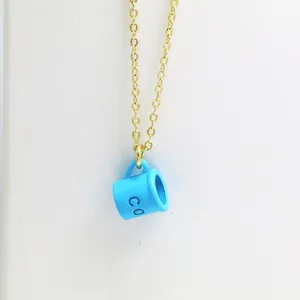 Detailed close-up of a creative blue coffee cup pendant necklace with a fine gold chain