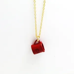 Detailed close-up view of a creative red enamel coffee mug pendant on a gold chain.
