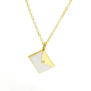 Detailed view of elegant gold envelope pendant necklace with white enamel and crystal