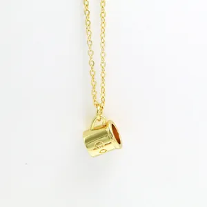 Detailed close-up of a gold-plated coffee cup pendant necklace with engraved lettering