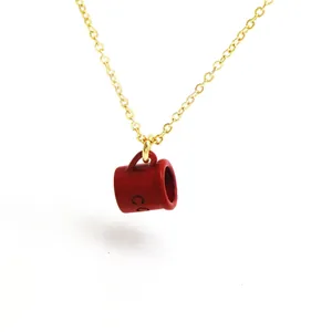 Detailed close-up of a red coffee cup pendant on a delicate gold chain necklace.