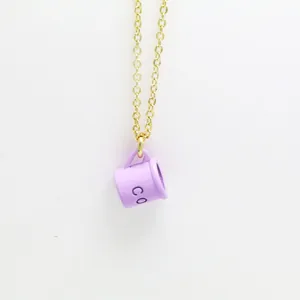 Detailed shot of creative purple enamel coffee cup pendant on a minimalist gold chain