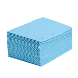 Large stack of disposable light blue waterproof nail table mats and dental bibs for salon use