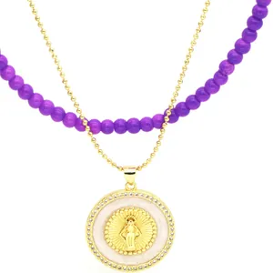 Close-up of double-layered necklace with purple beads and gold-tone religious pendant