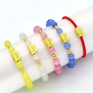 Nahaufnahme von Drachen-Zodiac-Armbändern mit bunten Katzenaugen-Perlen und roter Seidenschnur