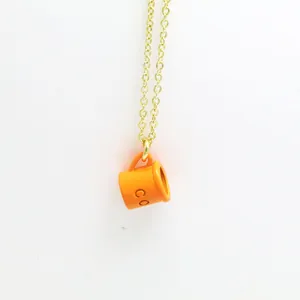 Detail view of a creative orange coffee cup pendant on a gold-tone delicate chain