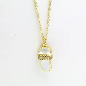 Close-up of a creative gold slipper pendant necklace with white enamel and crystals.