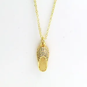 Close-up of golden slipper pendant necklace encrusted with shimmering white zircons