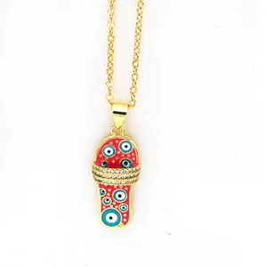Detailed macro shot of gold slipper pendant featuring red evil eye enamel and sparkling rhinestones