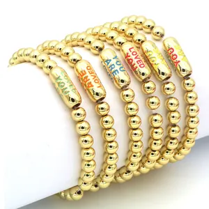 Close-up of 18k gold plated bead bracelets with colorful YOU ARE LOVED lettering detail.
