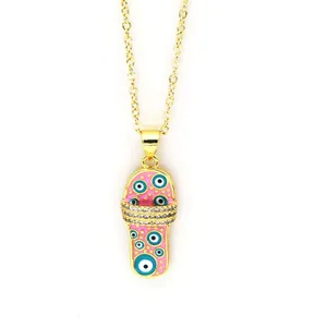 Detailed close-up of a pink enamel slipper necklace pendant with blue evil eye motifs