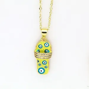 Macro detail of a gold slipper pendant featuring blue evil eye motifs and sparkling stones.