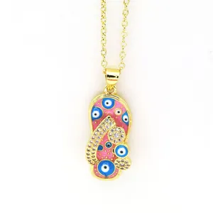 Close-up detail of gold slipper necklace with pink enamel drip oil and blue evil eye