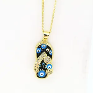Detailed macro shot of a gold-toned flip-flop pendant featuring blue evil eye charms.