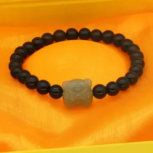 Detailed close-up of a black obsidian beaded bracelet with a carved jade tiger head charm