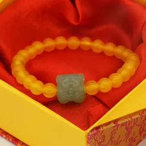 Macro detail of an agate bead bracelet featuring a carved green jade tiger head