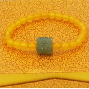 Detailed view of the handcrafted jade tiger charm on an orange agate beaded bracelet.