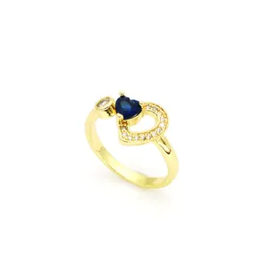 Gros plan d'une bague dorée avec un cristal bleu en forme de cœur et des pierres de zircon.