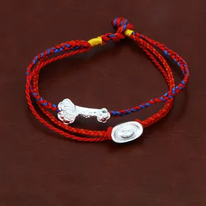 Detailweergave van een handgeweven rood en blauw touwarmband met zilveren bedeltjes