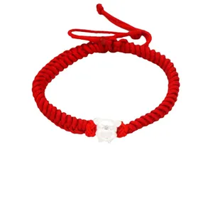 Macro-weergave van een handgemaakte rode armband met een 3D-zilveren dierenriem bedeltje.