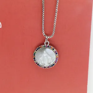 Close-up view of a Virgin Mary circular shell necklace featuring a colorful zircon border