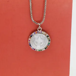 Macro detail of round shell pendant with colorful cubic zirconia border and silver chain