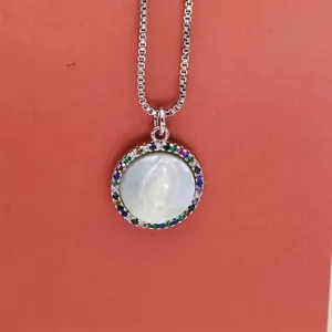 Macro shot of Virgin Mary carved shell pendant with colorful zircons and silver box chain.