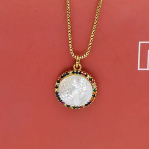 Detailed close-up of a Virgin Mary shell pendant necklace with multi-colored zirconia