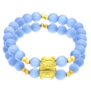 Detailansicht des hellblauen Katzenaugen-Armbands mit süßem goldenen Drachenanhänger