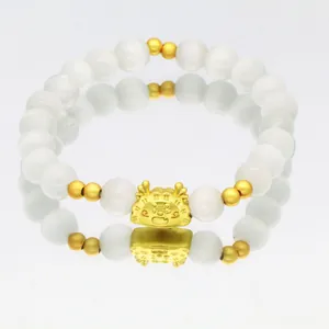 Detailansicht eines eleganten Katzenaugen-Armbands mit einem goldenen Drachenanhänger.